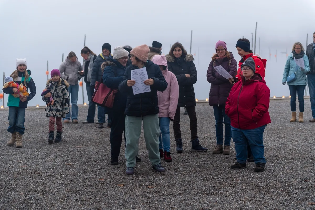 Menschen stehen am Seequai und halten Singblätter in den Händen.